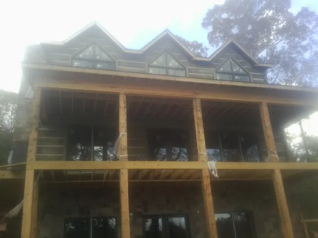 Dormers and porch framing on a large log home under construction — Roof Coating work by our crew in Fairburn