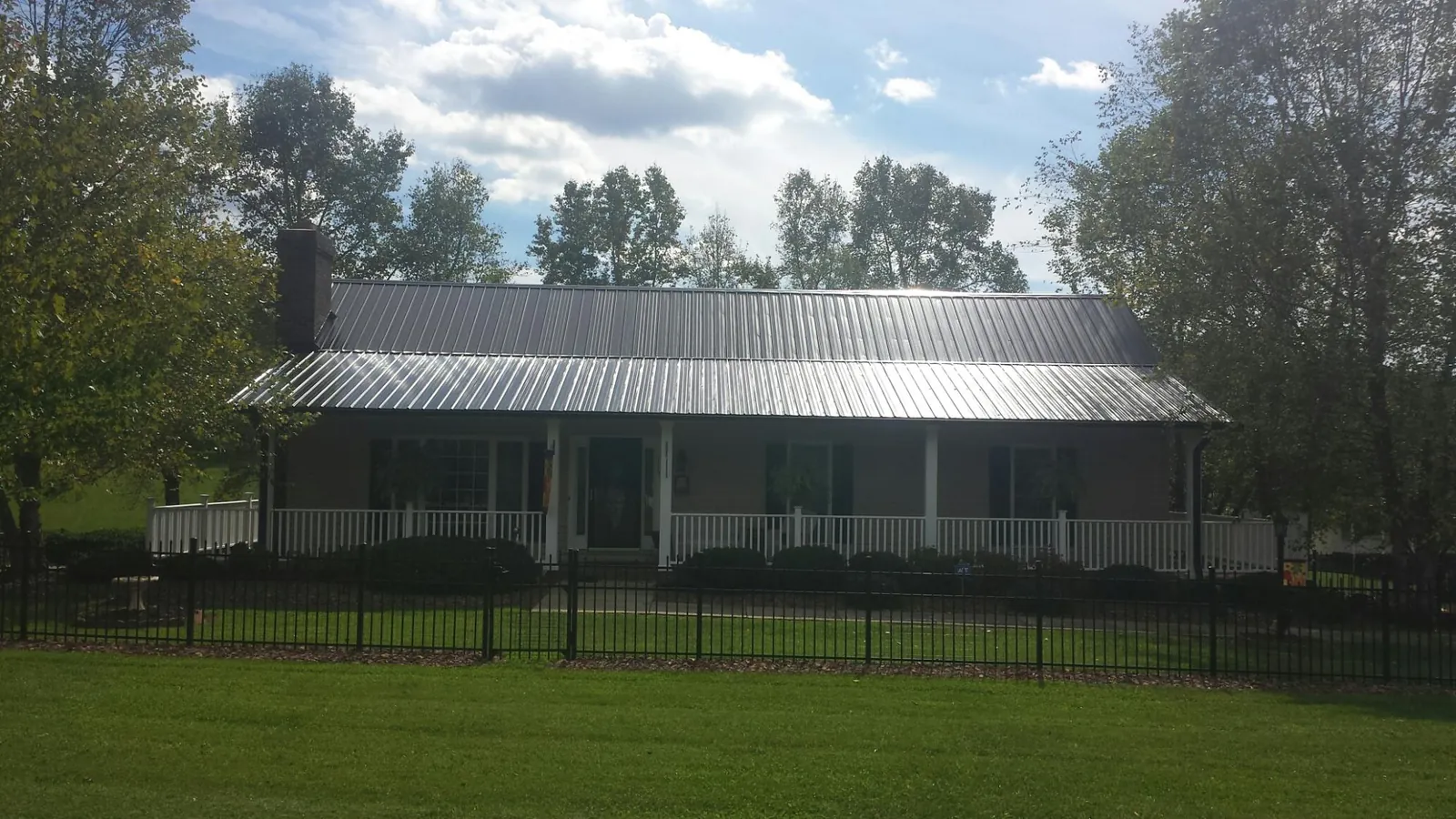 Gray metal roof on a brick ranch with a full width front porch — Gutter Guard Installation work by our crew in Fairburn