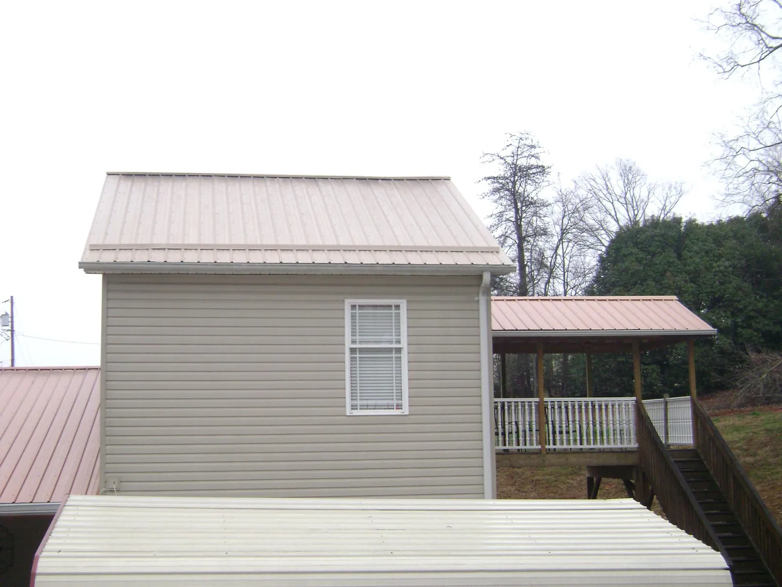Tan metal roofs on a two story addition and attached porch, from a Roof Replacement job in Fairburn