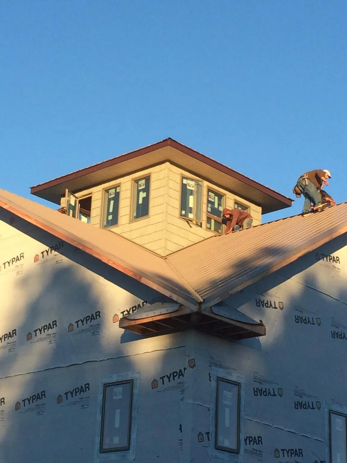 Roofers working around a rooftop cupola on a new metal roof at sunset — Roof Waterproofing in Fairburn by Roofing Brothers